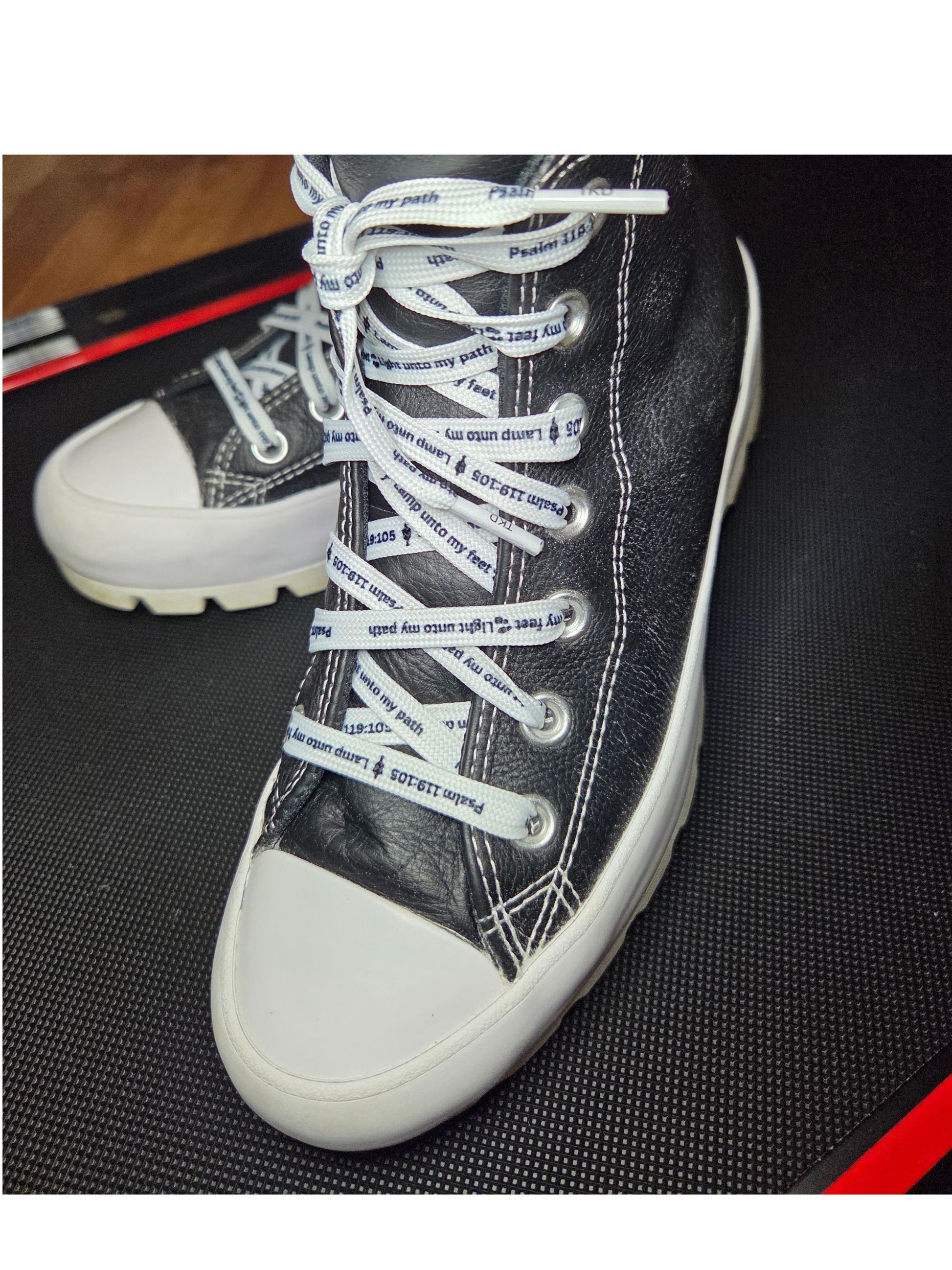 White faith shoelaces with Psalm 119:105 verse laced in sneakers on wood floor